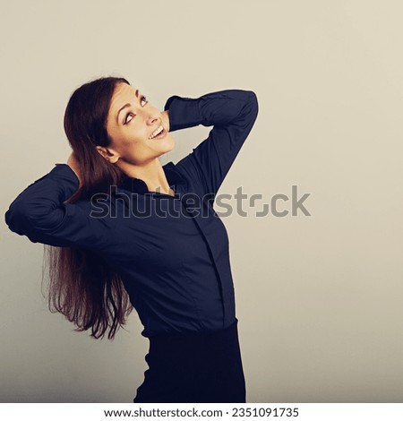 Beautiful happy smiling woman with long brown healthy hair style holding arms behind the head and looking up in blue shirt, formal clothing. Closeup toned color portrait with empty copy space