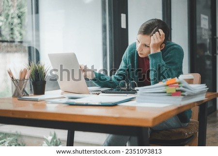 Serious focused woman looking at laptop screen, touching chin, sitting at desk, home office, thoughtful businesswoman pondering strategy, working on online project, searching information