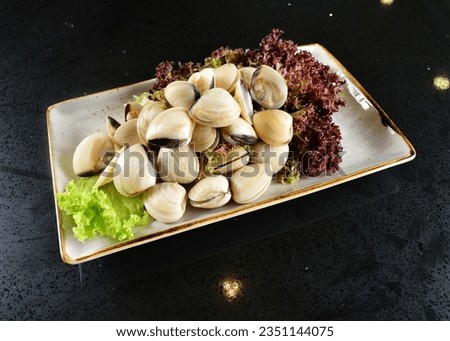 iced mixed raw seafood platter scallop, fish, crab, clam, shell, prawn, squid, oyster in bowl for steam boat on black marble table asian halal food cuisine menu for restaurant