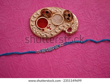 Blue Thread rakhi on textured paper background with kumkum and rice designed pot for rakshabandhan festival