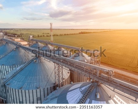 Modern metal silos on agro-processing and manufacturing plant. Aerial view of Granary elevator processing drying cleaning and storage of agricultural products, flour, cereals and grain. Nobody. Royalty-Free Stock Photo #2351163357