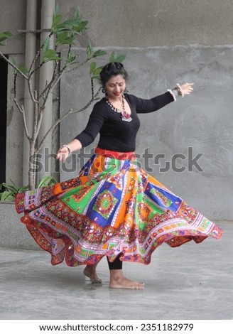 blurred effect. Restricted focus. Indian woman wearing multicolor ghaghra - chaniya for playing garba in Navratri.  her skirt flare rotates in the air as she dances on garba beats. festival attire.  Royalty-Free Stock Photo #2351182979