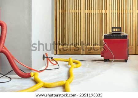 Water damage restoration service in a leaking home with industrial air movers, dehumidifiers and pipes to remove the water and moist from the wet floor and repair the house. Household insurance Royalty-Free Stock Photo #2351193835
