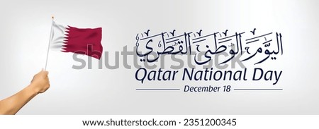 Qatar National Day banner. A hand holds Qatar flag. Arabic Translation "Qatar National Day". Vector EPS Royalty-Free Stock Photo #2351200345