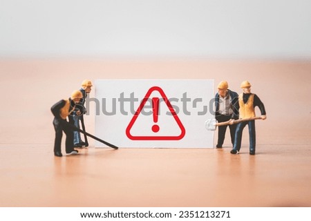 Worker and technician  miniature figure standing with caution exclamation sign to waring everybody work with safety first concept.
