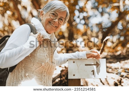 Portrait of happy attractive senior woman with backpack walking in the forest enjoying freedom, nature and healthy retirement lifestyle