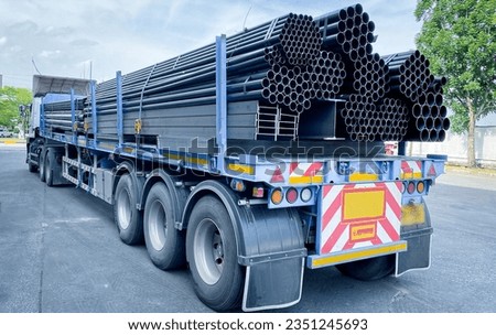 Trucks with long trailers carrying steel bars for building construction. Construction steel is ready to be delivered to the customer. Royalty-Free Stock Photo #2351245693