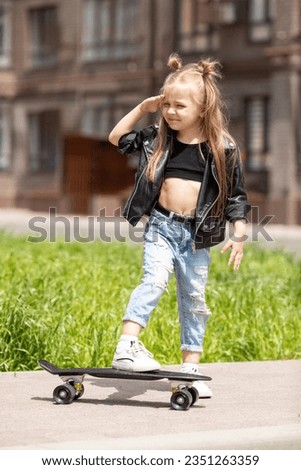 A Pretty little girl learning to skateboard outdoors on beautiful summer sunny day