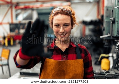 Young woman in STEM smiling showing product in her hand to the camera, workshop in background