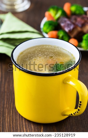 Homemade hot chicken soup in yellow mug for winter