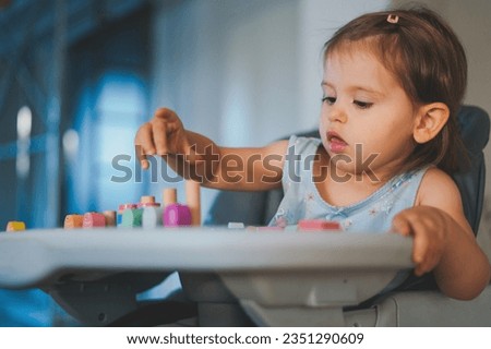 Little toddler playing on the table in a wooden magnetic constructor, learning at home to make puzzle. Early development. Playing with children during