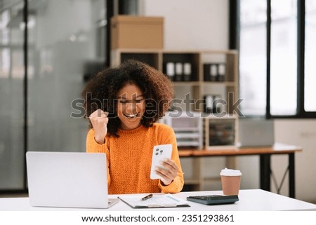 Overjoyed charming excited black woman business woman worker using smartphone working in office, feeling happy. Royalty-Free Stock Photo #2351293861