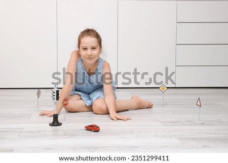 cute little girl playing at home on the floor with a typewriter, road signs and traffic lights