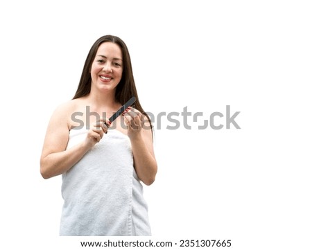 Happy young brunette woman smiling and wearing a towel while holding a nail filer against a white background