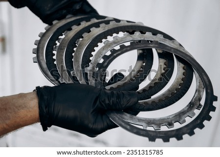 A man holds automatic transmission clutches in his hands. Gearbox replacement, repair work in a car service or garage. Assembly of automatic transmission, disassembly of parts.  Royalty-Free Stock Photo #2351315785