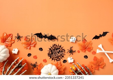 Happy Halloween concept. Flat lay composition with bats, ghost, pumpkins, skeleton hands, fallen leaves on orange background.