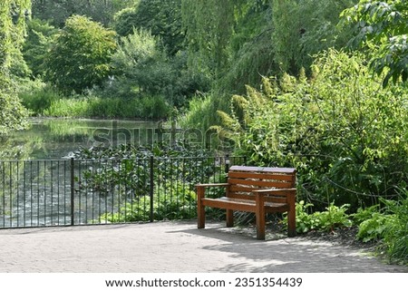 A wooden bench next to a pond in Royal Botanic Garden Edinburgh