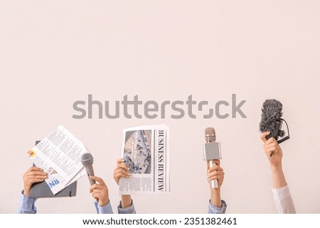 Female hands with newspapers and microphones on light background Royalty-Free Stock Photo #2351382461