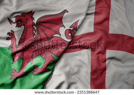 big waving national colorful flag of wales and national flag of england . macro