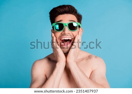 Photo portrait of attractive young man hands cheeks astonished impressed shirtless isolated on blue color background summer vacation