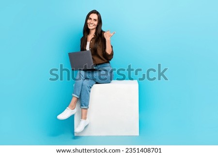 Full body photo of satisfied businesswoman sitting podium directing finger empty space freelance website isolated on blue color background