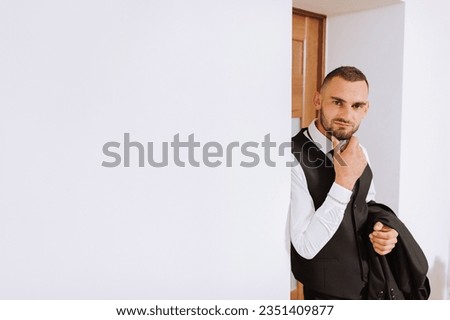 portrait of a man in a white shirt, waistcoat and black tie in a room with natural light. The groom is preparing for the wedding. The man is wearing a white shirt. Stylish groom