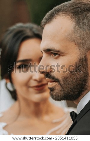 Portrait of a happy newlywed wife and husband hugging outdoors and enjoying a wedding bouquet of white roses. Sincere feelings of two young people. The concept of true love.