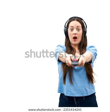 Surprised young brunette woman wearing headphones while holding a remote control against a white background