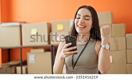 Young beautiful hispanic woman ecommerce business worker using smartphone celebrating at office