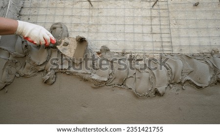 The construction surface of the facade wall of the building with a fixed mesh for cementing and painting the facade. Cement fixing mesh attached to a rough cement wall. 