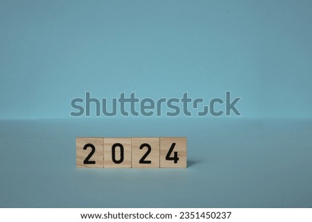New Year 2024. Wooden blocks date 2024 on blue background . concepts of achieving goals, plan, strategy, new ideas.