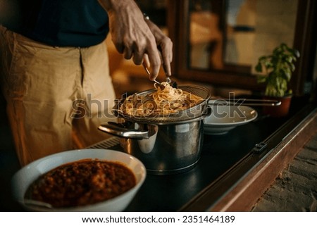 The male host prepares a pasta spaghetti at home, ready to serve to his friends and family.