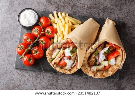 Chicken gyros with vegetables, french fries and tzatziki sauce closeup on the board on the table. Horizontal top view from above
 Royalty-Free Stock Photo #2351482107