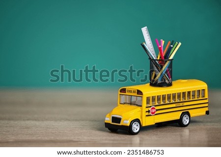 Toy school bus, back to school concept. Creative composition of yellow school bus carrying variety of school supplies. Royalty-Free Stock Photo #2351486753