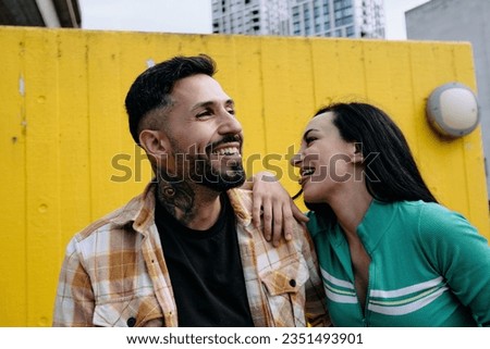 A man and woman share a laugh together as they have fun in a downtown city area.