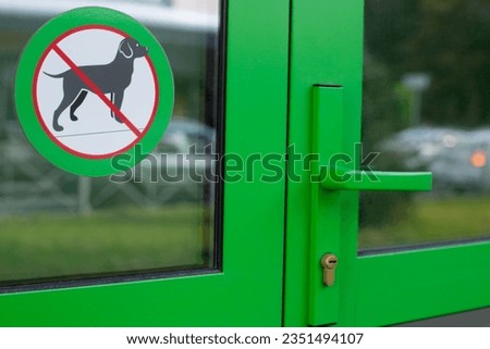Sticker on the glass at the entrance to the building with a crossed-out dog. Sign prohibiting entry with a pet is hanging near the green door