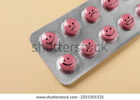 Pink pills with different emotional faces in blister on beige background