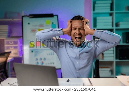Asian businessman or employee feels like going crazy after hard work and overtime. Asian Male employee who is stressed and tired from working overtime late at night. Royalty-Free Stock Photo #2351507041