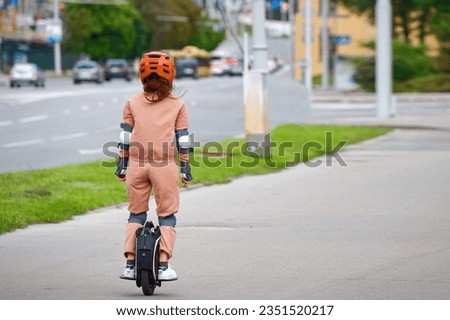 Woman in protective gear riding electric unicycle, monocycle or mono wheel. Trendy woman in helmet on electric vehicle, view from back. Woman ride electric mono wheel, personal electric transport Royalty-Free Stock Photo #2351520217