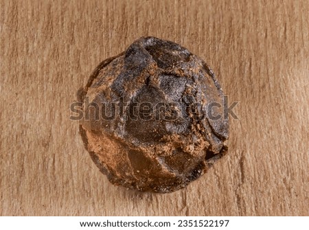 A macro shot of a single black peppercorn.