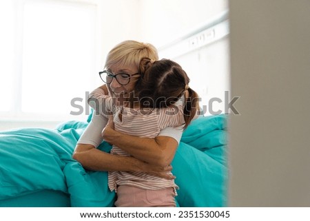 Touching photo of grandmother and female child while embracing each other and smiling, while being in hospital. Royalty-Free Stock Photo #2351530045