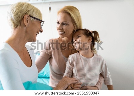 Portrait of beautiful daughter and granddaughter while visiting lovely smiling grandma in hospital.