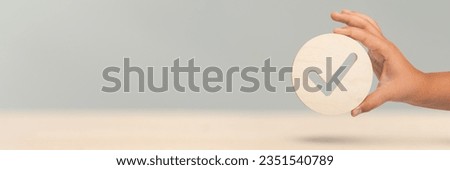 Hand holding check mark icon, banner with wooden check mark icon in hand, right sign. On a blue background. Copy space. Place for text