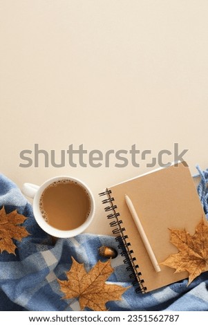 Warm desk setup in fall shades. Top view vertical photo of patchy blanket, pen, copybook, acorns, dry autumn leaves on pastel beige background with empty area for ad or note