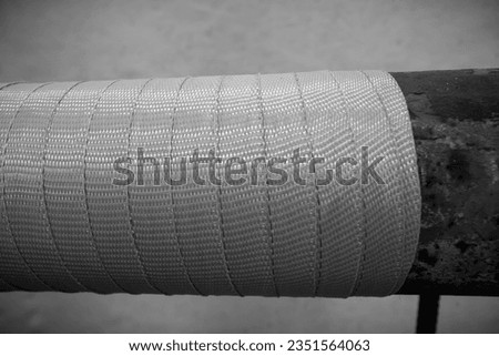 A fragment of the winding of a Kevlar tape in preparation for the composite repair of a drinking water supply pipeline. Royalty-Free Stock Photo #2351564063