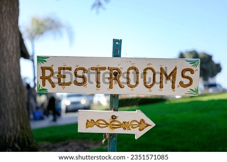 Restroom sign with blue sky and grass background. 