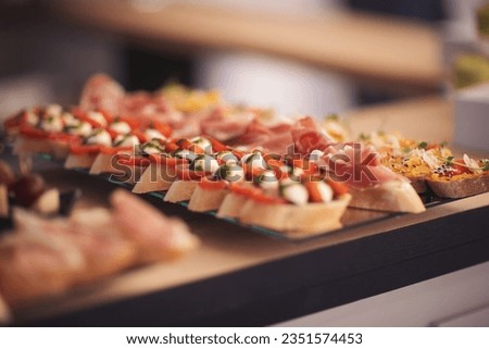 Snacks for the holiday, catering. Various light snacks. Catering plate. Assortment of sandwiches on the buffet table. meat, fish, nuts, cheese, vegetable canapes ofcelebration of important event.  Royalty-Free Stock Photo #2351574453
