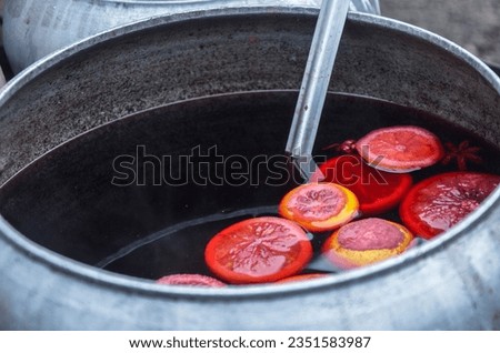 Hot aromatic tasty mulled wine with citrus fruits and spices, in a cauldron at the fair. Classic autumn or winter drink