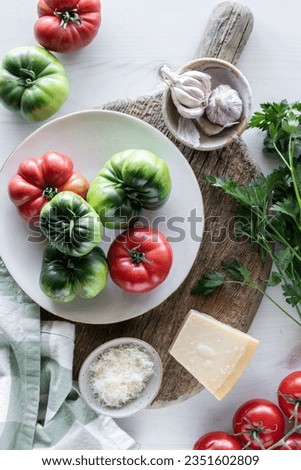 An arrangement of heirloom tomatoes on a rustic board with parmesan and parsley. Royalty-Free Stock Photo #2351602809
