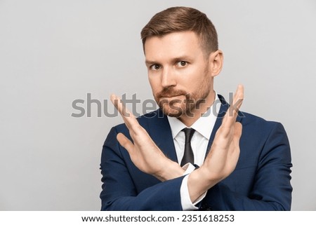 Serious businessman showing a stop sign of failure. Disagreeing indignant man in suit making disapproval gesture with hands, dislike, stop sign, looking at camera, isolated on gray studio background Royalty-Free Stock Photo #2351618253